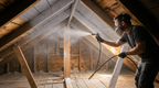 Radiant barrier paint spray coating on attic walls and beams from a sprayer