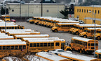 Multiple buses with white-coated RV roofs parked outdoors in rows