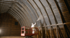 Radiant barrier paint misting attic ceiling beams from an elevated sprayer
