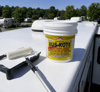 Protective RV roof coating can on a white roof with roller tray and nap cover