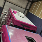 RV roof coating primer-coated roof panel on a vehicle in an indoor workshop