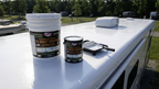 RV roof coating buckets and small can with roller tray on RV roof