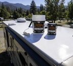 RV roof coating buckets and small can with paint roller on RV roof