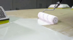 RV roof coating primer being rolled onto a flat roof surface with a white roller
