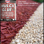 Mulch Glue™ container next to wood mulch and small gravel in a garden border area.